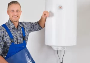 A Dinomite Service plumber stands beside a wall-mounted water heater during a residential water heater replacement in Springtown, TX.