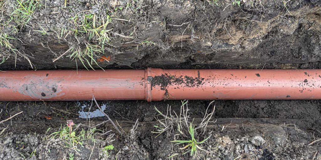 An underground clay or PVC plumbing pipe laid inside a soil trench, vulnerable to shifting from Weatherford’s expansive soil.
