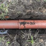An underground clay or PVC plumbing pipe laid inside a soil trench, vulnerable to shifting from Weatherford’s expansive soil.