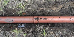 An underground clay or PVC plumbing pipe laid inside a soil trench, vulnerable to shifting from Weatherford’s expansive soil.